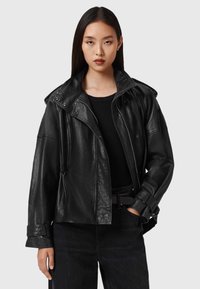 Zwarte leren jas met een hoge kraag, ritssluiting en voorzakken. Heeft een ontspannen pasvorm en een gestructureerde stof.