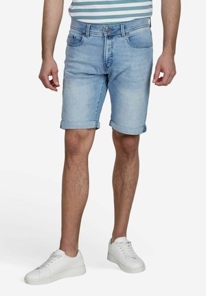 Shorts en denim bleu clair avec des revers, poches avant et fermeture à bouton, associés à des baskets blanches.