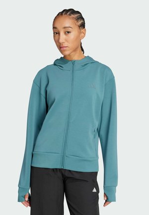 Sudadera con cremallera en color azul verdoso, hecha de una tela suave, con capucha, mangas largas con agujeros para los pulgares y un logo sutil en el pecho.