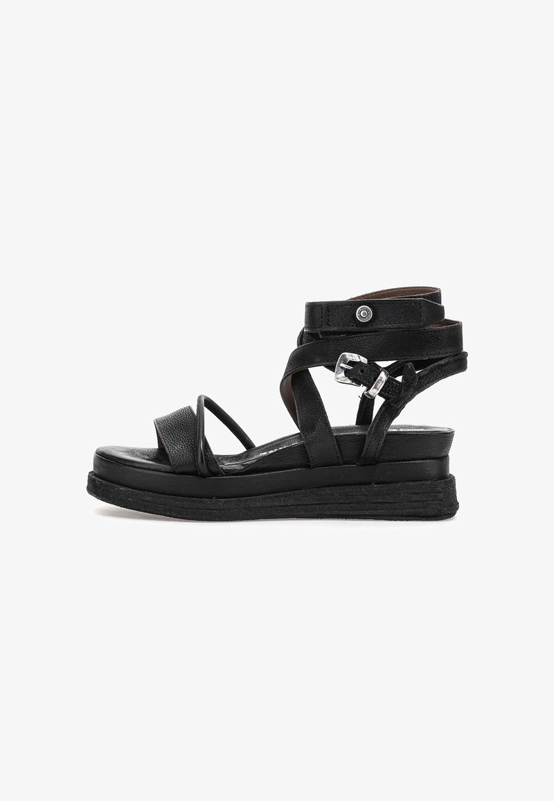 Černé kožené sandály na klínu s několika tenkými popruhy, obvazem kolem kotníku se sponou a texturovanou podrážkou, zobrazené v bočním profilu na bílém pozadí.