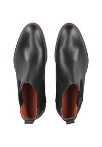 Botines de cuero negro con paneles elásticos en los costados, punta redondeada y interior naranja contrastante. Suela plana y lengüeta en el talón.