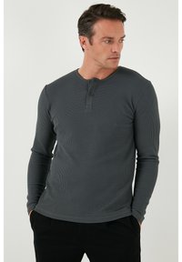Szürke, hosszú ujjú henley póló, textúrált váltott kötésű anyagból, kerek nyakkivágással és két gombos résszel, fitted ujjakkal és egyenes aljjal.