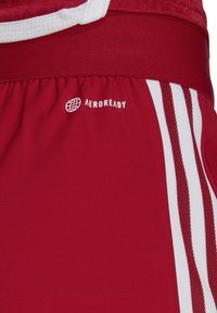 Rote Sportshorts mit weißen Akzenten, ausgestattet mit einem elastischen Bund und einem strukturierten Mesh-Oberteil. Enthält das "AEROREADY"-Logo.