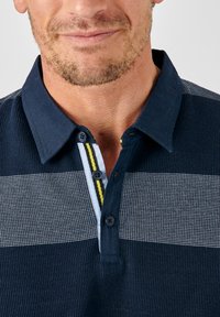 Navy-Polohemd mit strukturiertem Strickdesign, featuring horizontalen grauen Streifen, einem einfarbigen Kragen und einer Knopfleiste mit drei Knöpfen und gelben Akzenten.