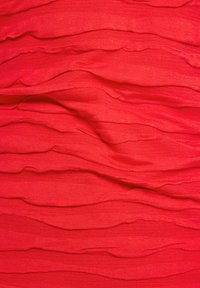Roter strukturierter Stoff mit gewelltem, plissiertem Design. Die Oberfläche wirkt weich und leicht glänzend, was die Tiefe durch überlappende Schichten betont.