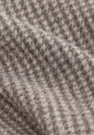 Wool fabric displaying a houndstooth pattern in light beige and dark brown, with a soft, textured surface and a slight sheen.