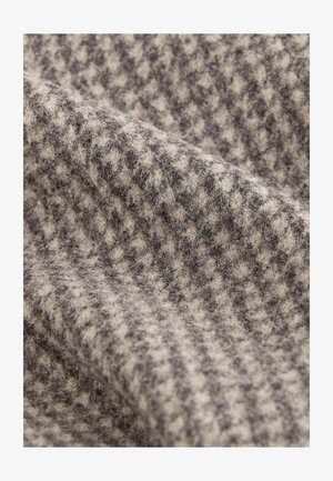 Wool fabric displaying a houndstooth pattern in light beige and dark brown, with a soft, textured surface and a slight sheen.