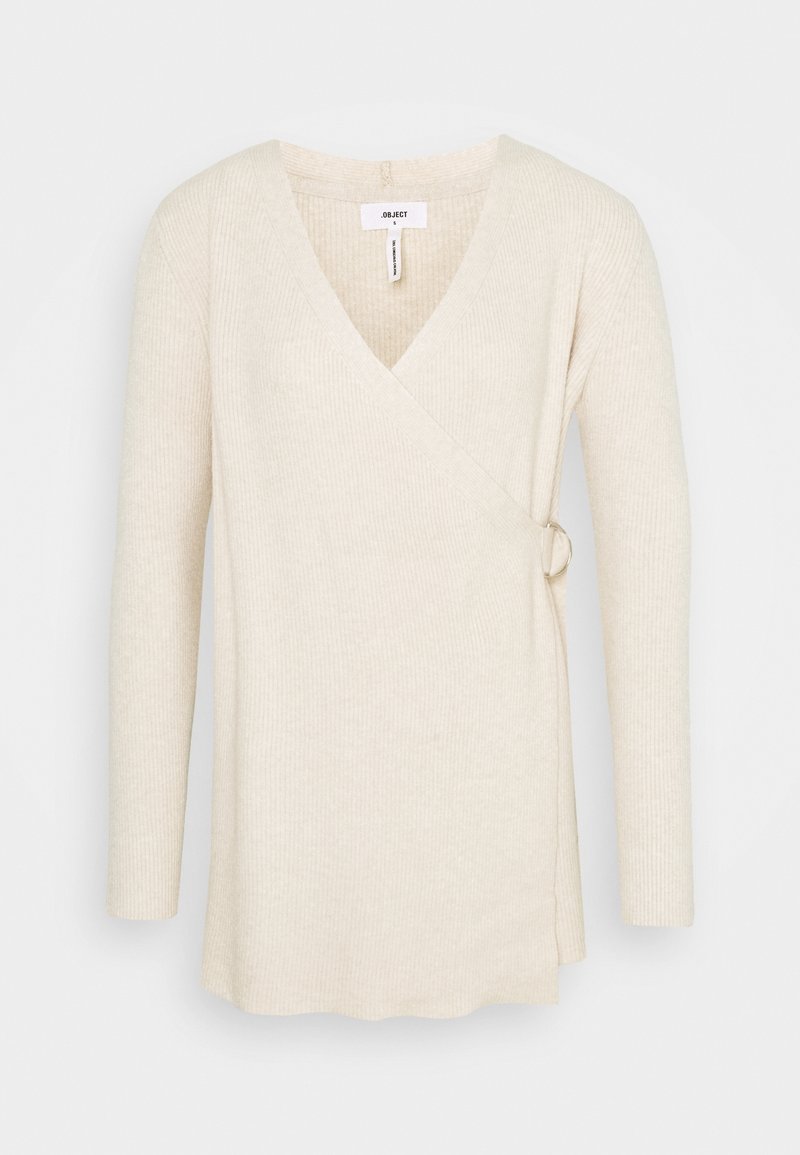 Pull enveloppant en maille côtelée couleur crème avec manches longues et détail de boucle sur le côté, taille petit.