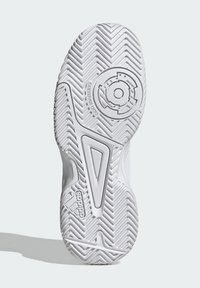 Semelle de chaussure de sport blanche avec un motif en chevrons, un détail d'adhérence circulaire et des accents texturés ; marquée comme non marquante.