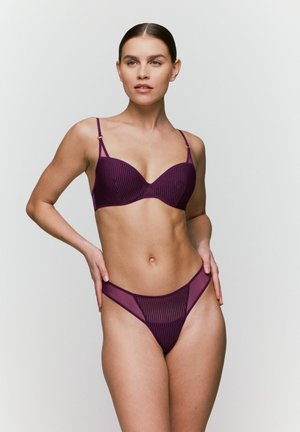 Paarse geribbelde bikini met dunne bandjes en gouden accenten. De beha heeft een gecontourde snit, terwijl de onderkant een hooggeknipte stringontwerp heeft.