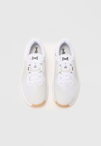 Pair of white athletic shoes with textured mesh design and tan soles, featuring lace tuck system and black branding on tongue and insole.