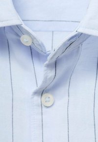 Cuello de camisa a rayas azul claro, con cierre de botón y costuras negras contrastantes. Tejido nítido con textura suave.