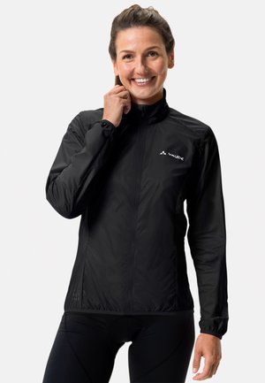 Veste légère noire avec une fermeture éclair à l'avant, col haut et poignets élastiques. Présente un logo sur la poitrine gauche et une texture lisse.