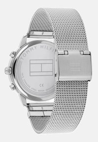 Orologio in acciaio inossidabile con cinturino a rete, finitura cromo, cassa rotonda e quadranti cronografici. Marchio distintivo sul retro. Resistente all'acqua.