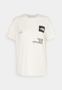 Camiseta de color crema hecha de algodón. Presenta un parche de logo negro y el texto "NUNCA DEJES DE EXPLORAR" con coordenadas en impresión negra. Mangas cortas.