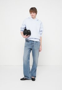 Hanorac cu glugă de culoare bleu deschis, blugi deteriorați de culoare albastră și geantă neagră. Croială lejeră, design simplu, cu o textură subtilă pe material.