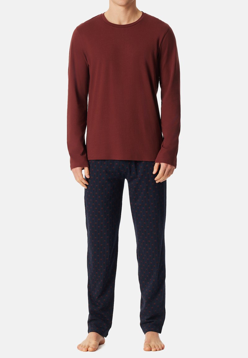 Červená košile s dlouhým rukávem v kombinaci s námořnicky modrými pyžamovými kalhotami s potiskem, které mají malé červené akcenty, z bavlny a volného střihu.