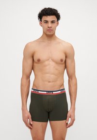 Olíva zöld boxer alsónadrág fehér, piros és sötétkék derékkal, "Levi's" logóval; puha anyagból, testhezálló dizájn.