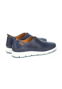 Zapatos de piel navy sin cordones con diseño perforado, que presentan un acento tejido en el talón y una suela blanca. Forro interior marrón.