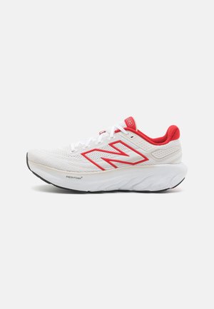 Hvid og rød New Balance løbesko med tyk hvid sål og logo på siden, vist fra ydersiden på hvid baggrund.