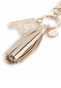 Ciondolo in acrilico trasparente con pagliuzze dorate, anello in metallo color oro e nappina in faux pelle beige. Include un piccolo medaglione inciso.