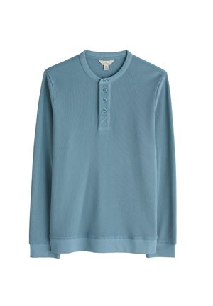 Hele sinine pika varrukaga henley särk, millel on tekstureeritud ribadesign, ümmargune kaelus, kolme nupuga pilu ja elastsed mansetid.