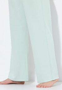 Licht mintgroene wijde broek van zachte stof, met een rechte snit, gestikte details langs de naden en een elastische tailleband.