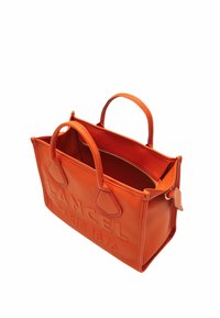 Sac fourre-tout en cuir orange avec deux poignées courtes, logo en relief et une poche zippée à l'intérieur. Texture lisse avec une forme structurée.