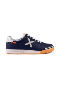 Zapatilla deportiva navy con suela de goma, cordones blancos y detalles en gris. Presenta una parte superior perforada y detalles en naranja cerca de la lengüeta.