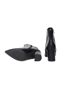 Un paio di stivaletti neri in pelle con tacco a blocco, uno stivale in posizione verticale e l'altro sdraiato su un lato che mostra la suola.