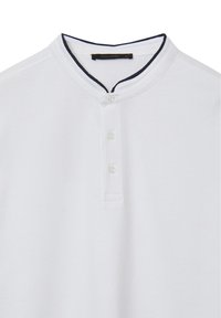 Chemise henley blanche avec col bleu marine contrastant, patte de boutonnage à trois boutons et tissu texturé. Étiquette de la marque indiquant "CALLIOPE" taille XL.