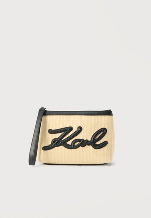 Pochette rectangulaire beige avec fermeture éclair et bordure noires, bracelet noir pour poignet, et logo "Karl" en cursive noire sur le devant.