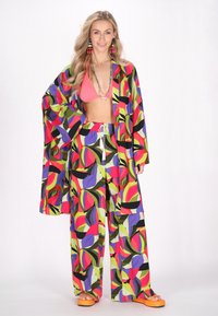Färgglad kimono-liknande överdrag med vida ärmar, parat med matchande lösa byxor. Färgerna inkluderar rosa, grön, lila och svart.