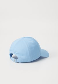 Világoskék baseball sapka ívelt karimával, állítható pánttal a hátsó részen, és varrott részletekkel az illesztéseknél. Simább anyagtextúra.