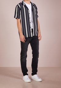 Kortärmad skjorta i marinblått med vita vertikala ränder; knapplåst framsidan, en bröstfickan, bärs med svarta jeans och vita sneakers.