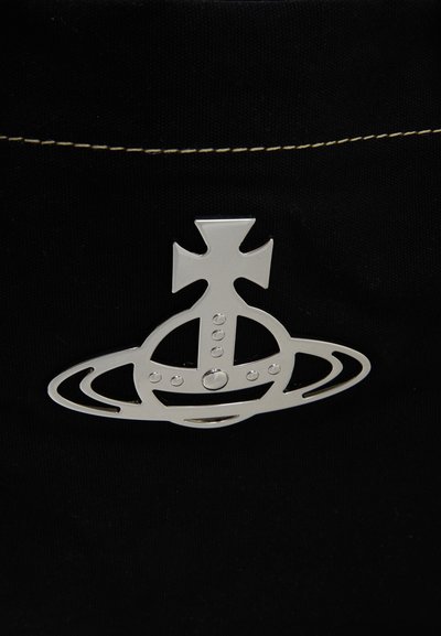 Srebrny metaliczny emblemat łączący krzyż i pierścienie przypominające orbitę Saturna, przymocowany do czarnej tkaniny z widocznym białym szwem u góry.