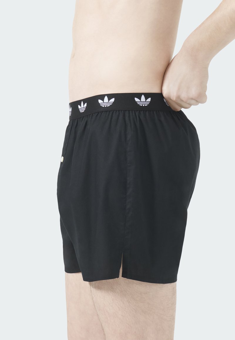 Schwarze Shorts mit elastischem Bund, weißen Adidas-Logo-Akzenten, leichtem Material und seitlichen Schlitzen für mehr Bewegungsfreiheit.