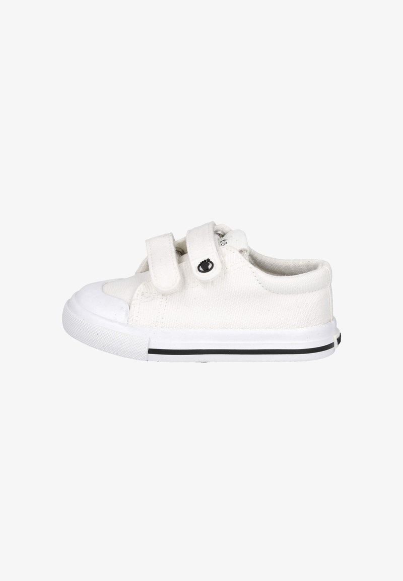Zapatilla para niños pequeños de lona blanca con dos tiras de velcro, puntera de goma y raya negra en la suela blanca, vista lateral sobre fondo liso.