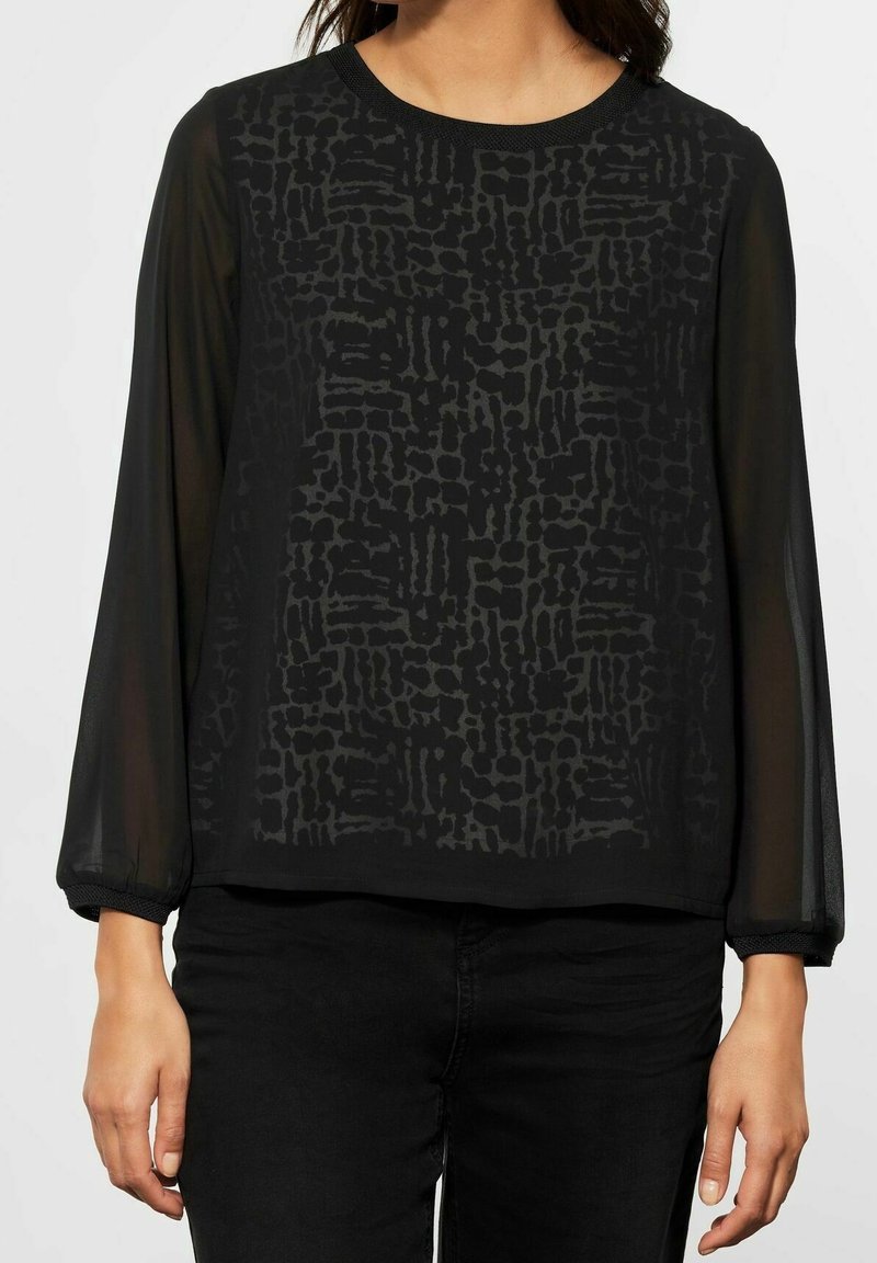 Zwart blouse met doorzichtige lange mouwen, gestructureerd patroon in een donkerdere schaduw van zwart, ronde halslijn en elastische mouwen.