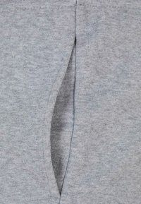 Tissu en polaire gris avec une fente latérale verticale. Texture douce et design décontracté, avec une finition soignée sur les bords.