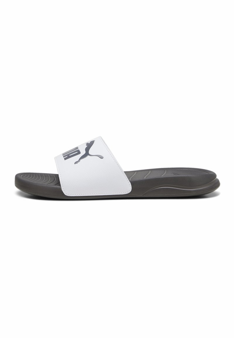 Bijele sandale na klizanje s širokim remenom na kojem je crni Puma logo, sivi teksturirani ulošci i crna izdržljiva potplat. Minimalistički dizajn.