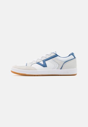White and blue low-top sneakers featuring perforated panels, a textured toe cap, and a gum rubber outsole, with a logo on the heel.