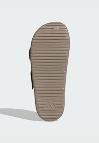 Beige sandaldør med en struktureret grip-mønster og ikonisk logo. Rund form med forhøjede kanter og en flad bund.