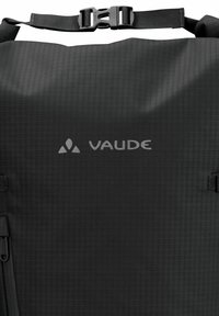 Sac à dos imperméable noir en tissu texturé, comportant un logo en forme de V, une sangle à boucle réglable et un compartiment zippé.