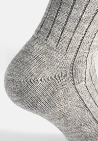 Calcetín de punto gris con un diseño acanalado, textura suave y talón reforzado. La costura visible añade detalle cerca del tobillo.