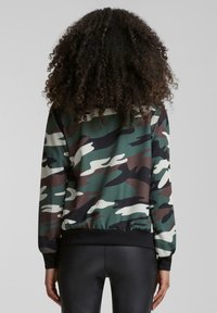 Tarn-Sweatshirt in grünen, braunen und weißen Tönen. Mit gerippten Bündchen und Saum sowie einem glatten, leichten Stoff.