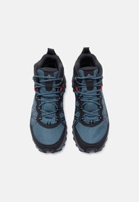 Ζευγάρι μπλε και μαύρα παπούτσια πεζοπορίας Columbia με γκρι κορδόνια και κόκκινα δέρματα, εμφανιζόμενα από πάνω σε λευκό φόντο.