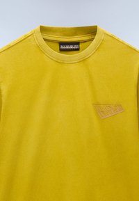Gul bomulds T-shirt med rund hals, der har præget logo detalje på venstre bryst. Glat tekstur og minimalistisk design.