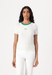 Camiseta de manga corta gris claro con un cuello acanalado verde. Presenta "GAP" bordado en verde en el centro. Fabricada con una tela texturizada.
