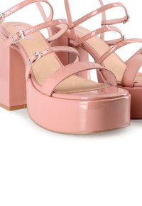 Sandalias de tacón alto de charol rosa con un tacón grueso, con múltiples correas finas y hebillas plateadas, textura suave.